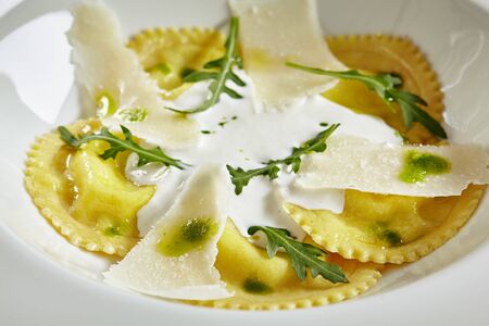 Exquisite Serving White Restaurant Plate of Ravioli 4 Cheeses with Cheese Espoume. Traditional Delicacy Italian Dumplings with Spinach and Arugula Close Upの写真素材