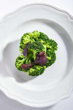 Top view of steamed broccoli on white restaurant plate isolated. Green asparagus cabbage cooked on steam, healthy veggie vegetables in vegan restaurent topviewの写真素材