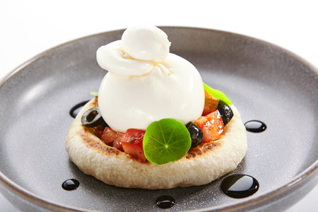 Burrata on rye pita with tomatoes and olives closeup view. Cow milk cheese with fresh cut vegetables and bakery. Food presentation, delicious restaurant dish. Traditional italian recipeの写真素材