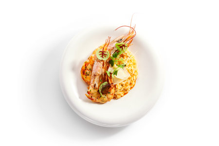 Risotto tom yam with argentinian shrimp. Delicious thai dish with seafood top view. Traditional asian meal with rice and aromatic greenery. Food composition on white plate. Restaurant delicacyの写真素材