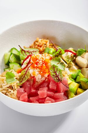 Poke with tuna and noodles. Hawaiian salad with avocado and tofu closeup view. Traditional polynesian dish with rice and cheese. Delicious native cuisine. Meal served with edamame, vegetables and soybeanの写真素材