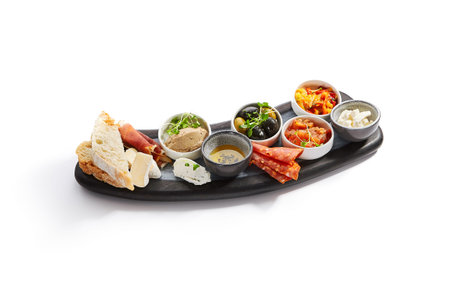 Wooden tray with snacks side view. Olives, burrata, jamon with pear. Bowls with liver pate, honey...