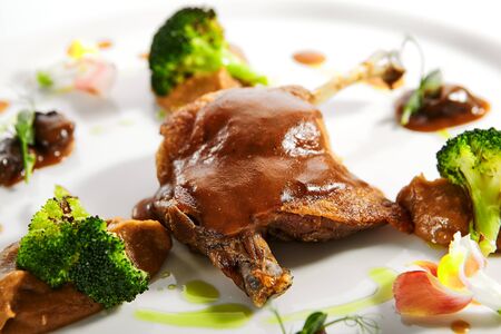 Confit duck leg with vegetables. Served meat with smoked cabbage puree and roasted broccoli. Restaurant food portion, main course in white plate close up. Cooked supper, plated dishの写真素材