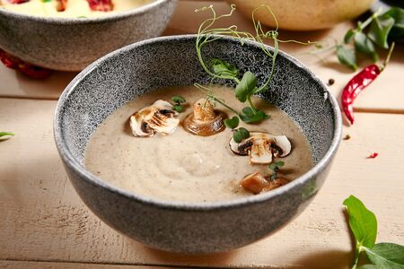 Forester soup with cheese rusks in gray bowl. Liquid dish, first course with greenery and mushrooms decoration close up. Served creamy broth, puree, mashed soup. Hot restaurant mealの写真素材