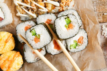Roll set pn parchment with chopsticks. Delicious sushi, asian cuisine, healthy nutrition, traditional japanese food with rice and fish close up. Served seafood, restaurant mealの写真素材