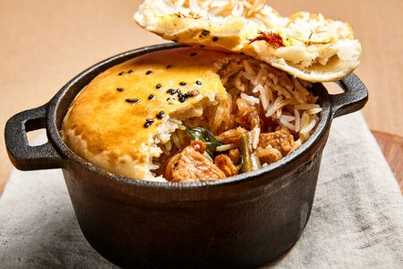 Chicken with basmati in dough. Poultry baked with rice in cast iron dish. Restaurant meal serving overhead shot. Fine food portion. Bread loaf with meat and vegetable filling. Cooking artの写真素材