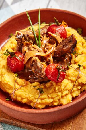 Hummus with beef served in brown bowl. Veal with vegetables closeup view. Meat with tomatoes in deep plate. Restaurant dish serving. Main course portion. Gourmet food shot. Cooking artの写真素材