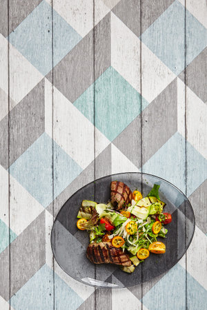 Salad with veal and kumquat. Restaurant meal served on transparent plate. Beef steak with raw...