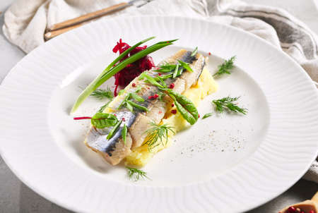 Herring Fish and Mashed Potatoes Plate. Garnished with green onion and beet salad. White restaurant plate on gray table. Salad, Healthy, Appetizer rustic food conceptの写真素材