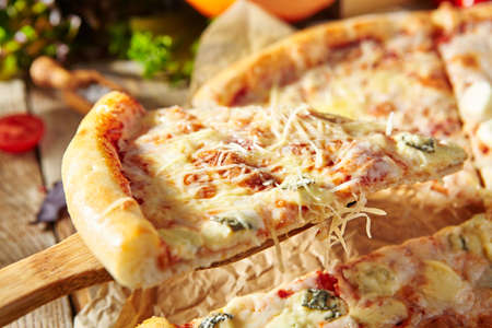 Four Cheese Pizza or Quattro Formaggi Pizza topped with tomato sauce, mozzarella, gorgonzola, Parmigiano Reggiano, and goat cheese. Pizza slice closeup viewの写真素材