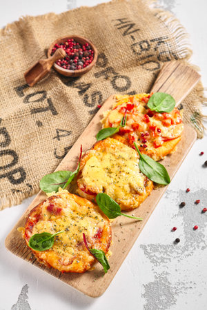 Mini pizza board on rustic white table. Pizza with cheese and tomatoes garnish with basil leaf. Small food conceptの写真素材