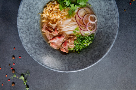 Vietnamese Cuisine - Beef Pho Noodle Soup or Pho Bo Soup. Served with Fresh Greens in Blue Bowl on...
