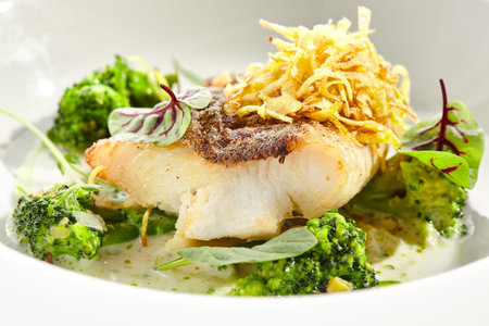Panfried Fish with broccoli and cream sauce. Healthy roasted cod with green leaves. Fried Fish on...