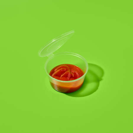 Sauce in plastic container on green background. Sauce package in minimal style. takeaway food. fast food menu. Portion of sauce for delivery. takeout dipの写真素材