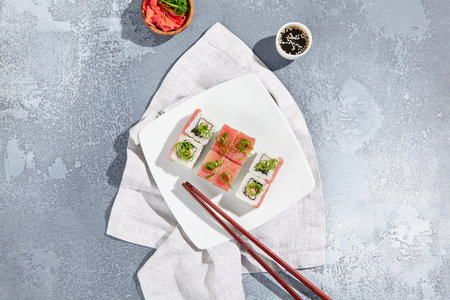 Maki sushi with tuna and green onion on wooden board in aesthetic composition. Simple sushi roll with tuna on concrete table. Fresh sushi roll in minimal styleの写真素材