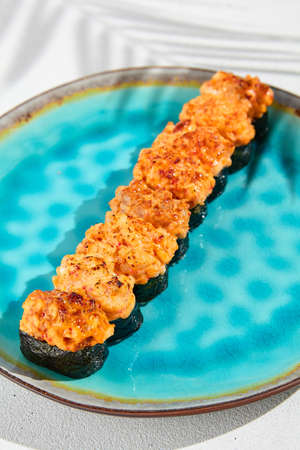 Set of baked gunkan on ceramic plate in minimal style. Hot gunkan sushi assorted with fish, crab, eel, tuna, shrimp and sea scallop. Simple sushi set on white background with hard shadowsの写真素材