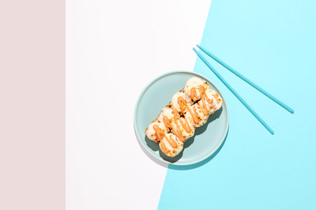 Hot maki roll with cheese on colored background. Baked sushi roll with chicken and bread crumbs,...