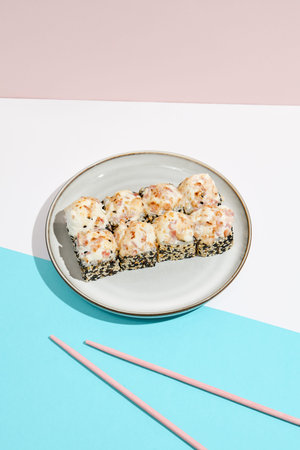 Baked Maki roll with bacon on ceramic plate. Hot sushi roll with sesame outside, bacon and cheese...
