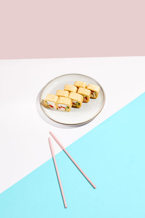 Sushi set on ceramic dishware with colored chopsticks. Trendy set of maki sushi in minimal style....