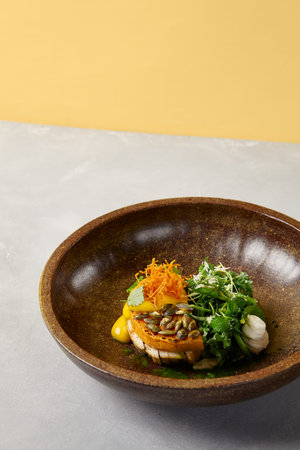 Pumpkin steak with chicken and spinach on dark ceramic plate. Healthy food in modern dishware. Innovative recipes in contemporary style. Roasted turkey with pumpkin on gray concrete backgroundの写真素材