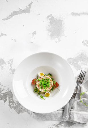 Original Russian potato salad with green peas and mayonnaise. Russian christmas menu. Olivier salad with boiled potatoes, carrots, eggs, peas and meat with mayo dressing. traditional new year dishの写真素材