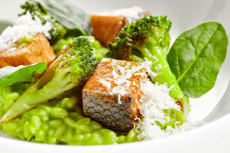 Gourmet food - green risotto with broccoli and salmon on white background. Italian lunch with risotto and sliced grilled salmon. Contemporary dish for restaurant menu. hard shadow in sunshine dayの写真素材