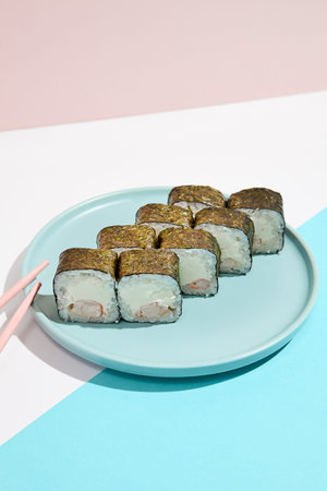 Simple cheese maki roll with shrimp on ceramic plate. Shrimp hosomaki in minimal style on colored...