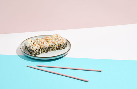 Baked Maki roll with bacon on ceramic plate. Hot sushi roll with sesame outside, bacon and cheese...
