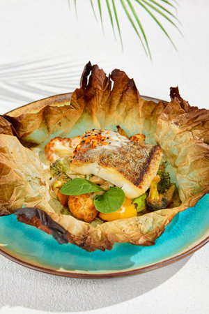 Baked halibut fillet with vegetables in parchment. Fish dish - roasted halibut with potato, broccoli...