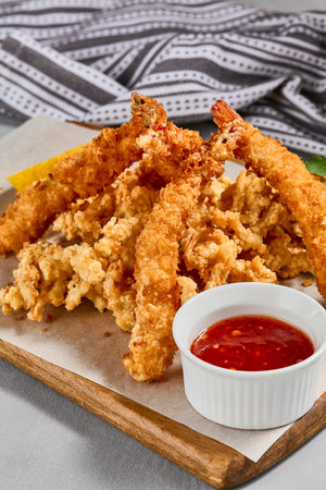 Traditional Asian appetizer - crispy shrimps with sauce. Tempura shrimps on wooden board. Prawn...