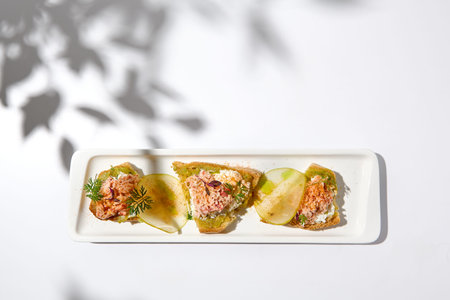 Aesthetic composition with crab bruschetta on white background with shadows from flowers. Italian...