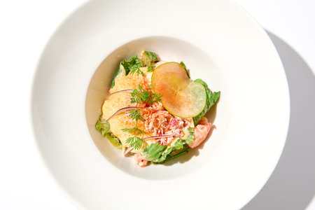 Elegant salad with crab meat, espuma sauce and lettuce on white table with harsh shadows. Green...