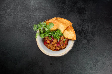 Chilli con carne with beans and corn tortilla on black background. Traditional mexican food - chilli...