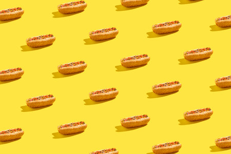 An American street food classic, cheesesteak with marbled beef, alive comes on a yellow background. Served in a sesame bun and paired with a vegetable salsa, the sandwich casts a hard shadow, creating a visually striking patternの写真素材