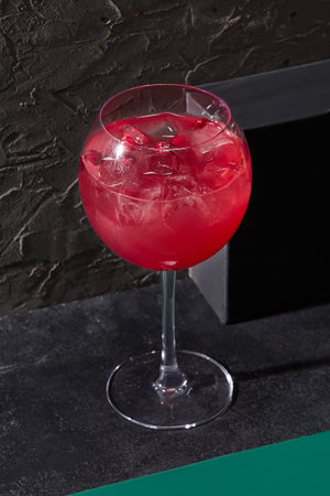 Minimalist presentation of berry lemonade in a wine glass, poised against a contrasting black backdrop. Perfect for a bar menu.の写真素材