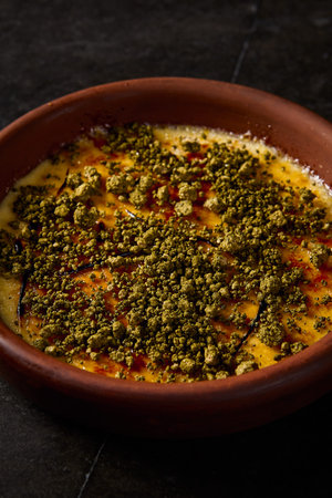 Vertical perspective close-up of crÃ¨me brÃ»lÃ©e with pistachio, capturing the clay dessert's...