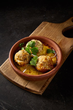 Close-up vertical side view of the selectable baked mushrooms, brimming with lamb and accented by cilantro, set on a Georgian 'keci' clay plate.の写真素材