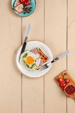Set a scene with a tempting Viennese waffle, garnished with bacon and egg, and presented on a beige wooden surface. Ample space lets the dish's minimalist beauty shine.の写真素材