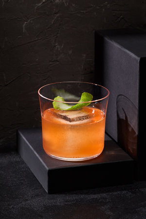 A contemporary gin and tonic infused with bergamot, elegantly set on podiums, exuding minimalist design against a stark black backdrop.の写真素材