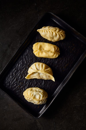 Top view close-up of Uzbek manty, emphasizing the details and flavors, set on a black plate atop a...