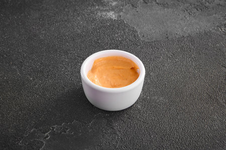 Spicy aioli sauce infused with red pepper presented in a white dipping bowl on a sleek black background.の写真素材