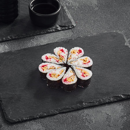 Droplet sushi roll featuring a fluffy Japanese omelet and tobiko caviar, tastefully arranged on a dark slate serving board.の写真素材