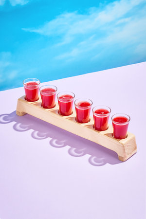 A vibrant set of cranberry shots on a wooden paddle, perfect for social gatherings.の写真素材