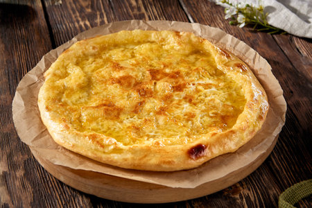 Golden-browned Megrelian khachapuri on parchment, with a rustic wooden backdrop, inviting and traditional.の写真素材
