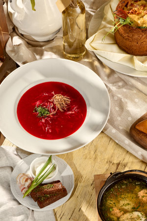 Borscht composition on a table with pork belly, garlic, and black bread, a Slavic dining staple.