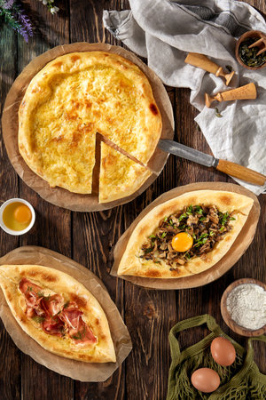 Assorted Georgian khachapuri; Adjarian with bacon and mushrooms, and Megrelian on a rustic wooden background.の写真素材