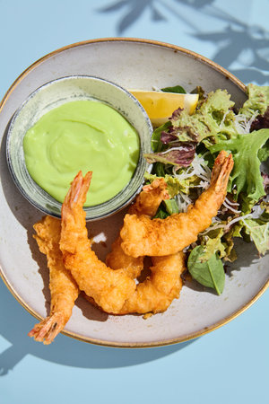 Artistic tempura shrimp with wasabi sauce, accompanied by summer blooms and soft pastel tones.の写真素材