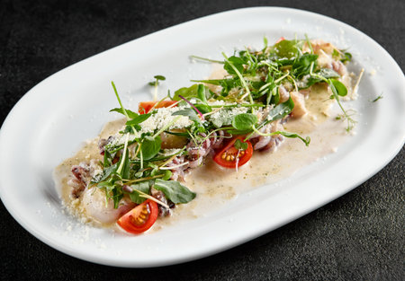 Creamy seafood assortment garnished with fresh greens and cherry tomatoes on a white oval plate.
