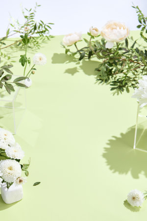 Minimalistic botanical display with white blooms and green foliage against a lime backdrop.の写真素材