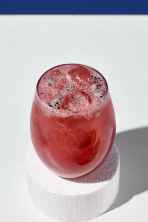 An exotic lemonade with dragon fruit, elegantly perched on a white pedestal, complemented by a bold blue background.の写真素材